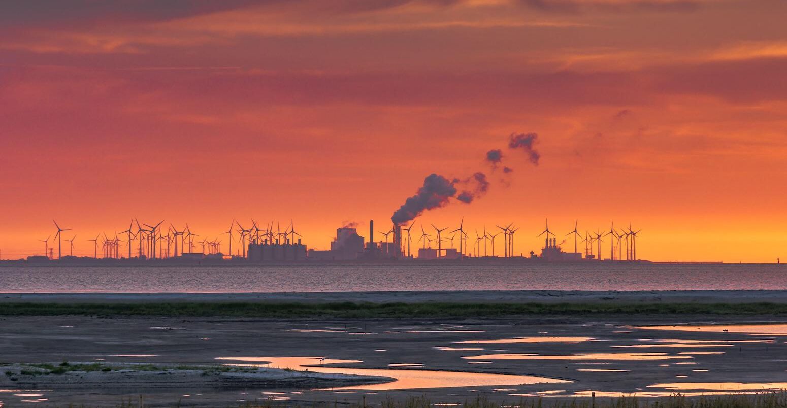 The Wadden Sea, factory buildings and wind turbines at sunset, Eemshaven, Netherlands.