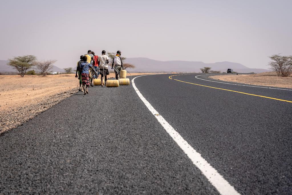 People transporting water along a highway in northern Kenya as climate change causes the worst drought in East Africa.