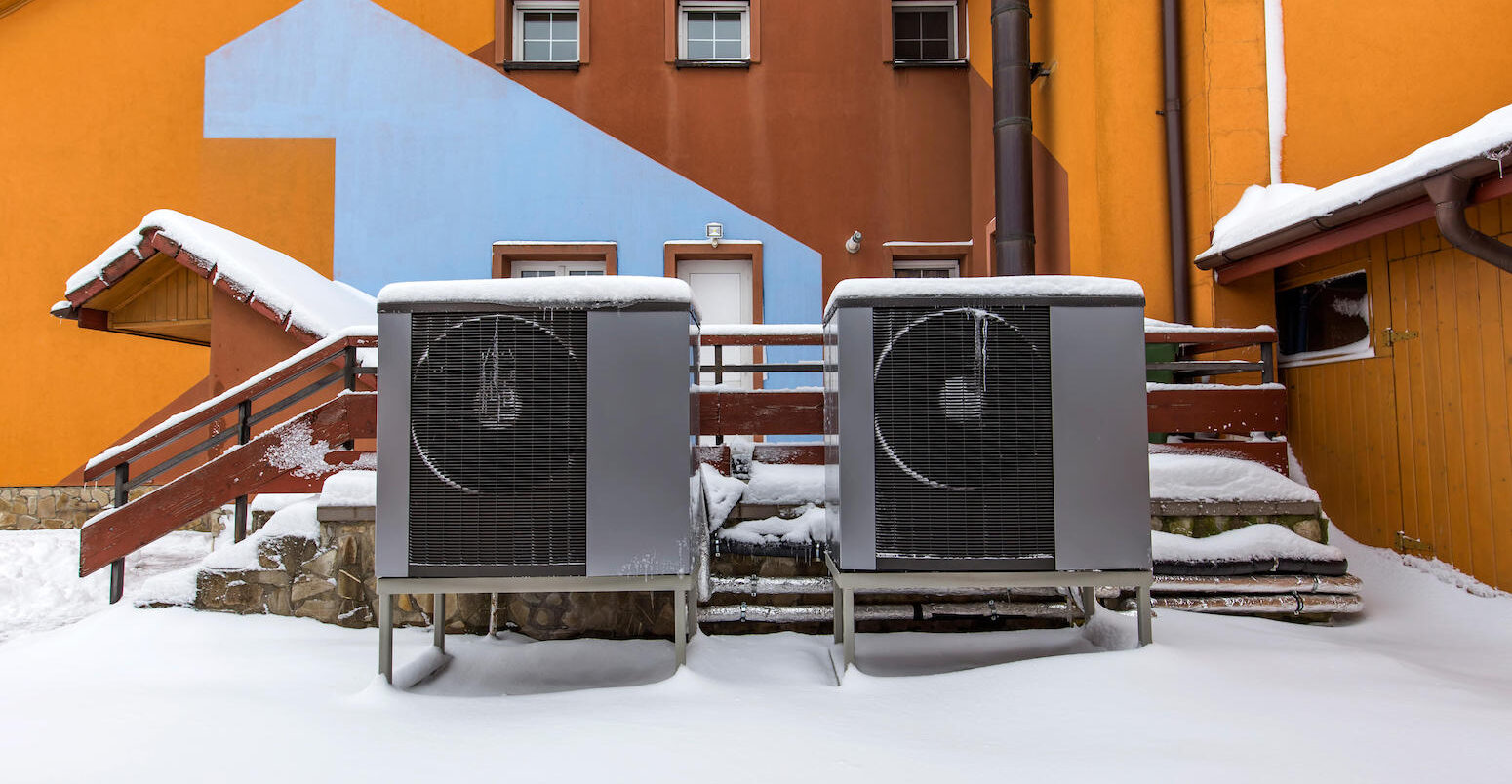 Two residential heat pumps buried in snow. Credit: Radu Sebastian / Alamy Stock Photo